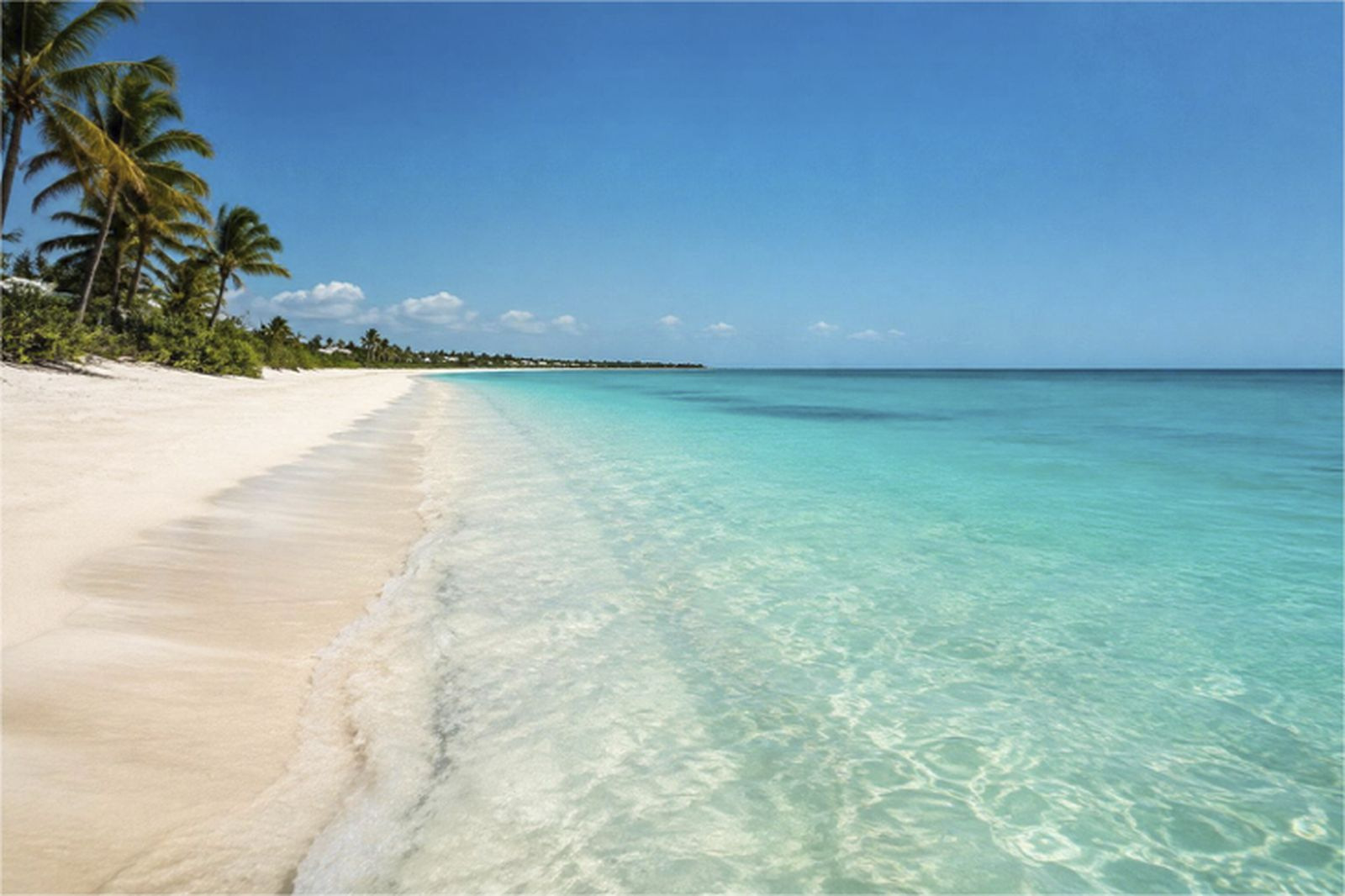 Pale turquoise shallows meeting a long empty stretch of white sand on a Turks and Caicos cay