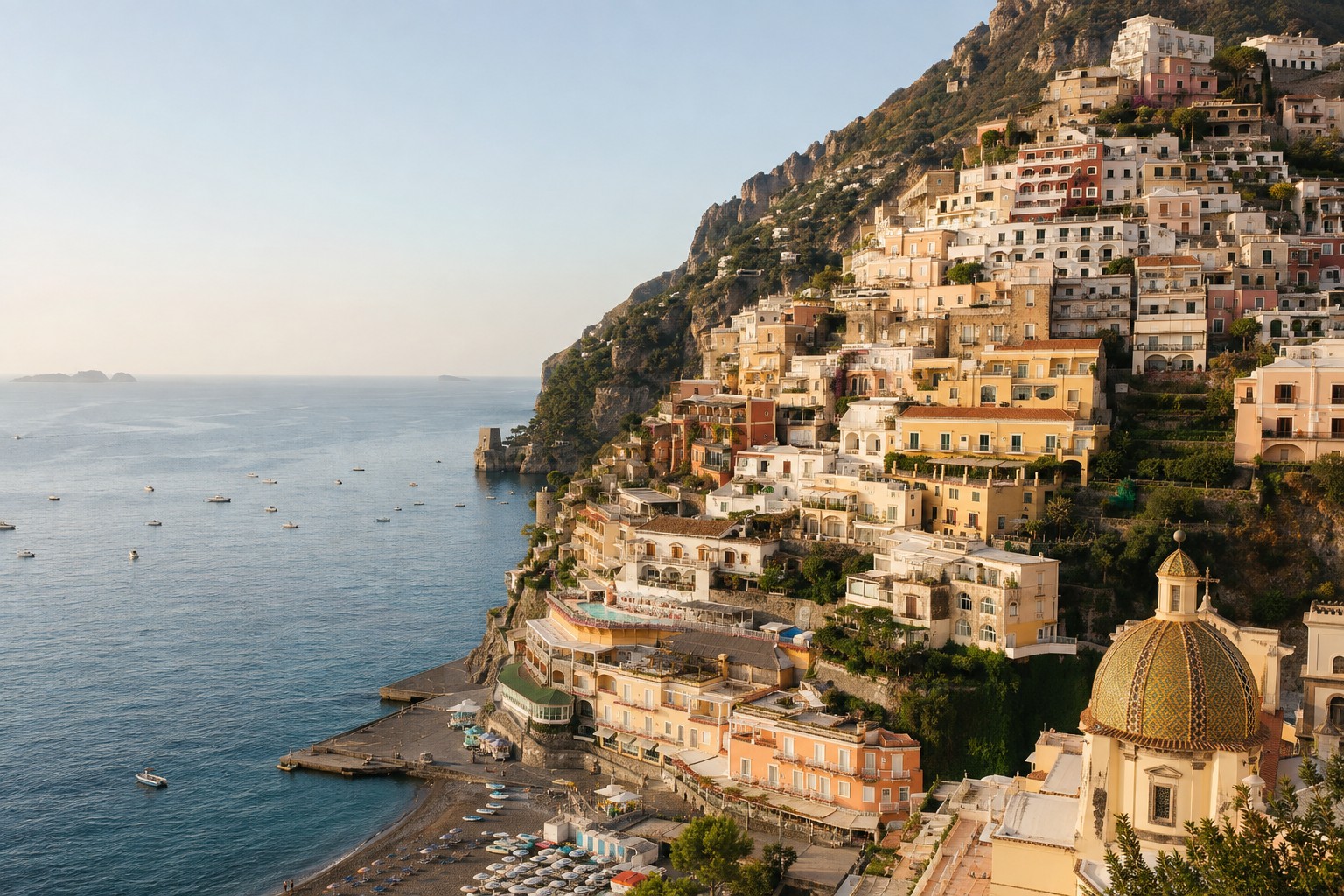 Pastel houses stacked down the cliff to the beach at Positano seen from the water