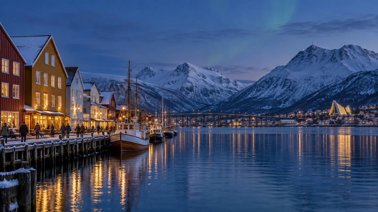 Tromsø harbor with colorful buildings, snowy mountains, and winter evening light