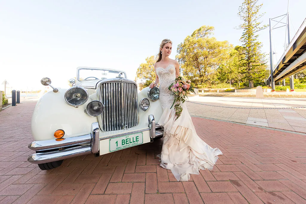 Classic Jaguar sedan wedding car outside a Perth stone church at dusk