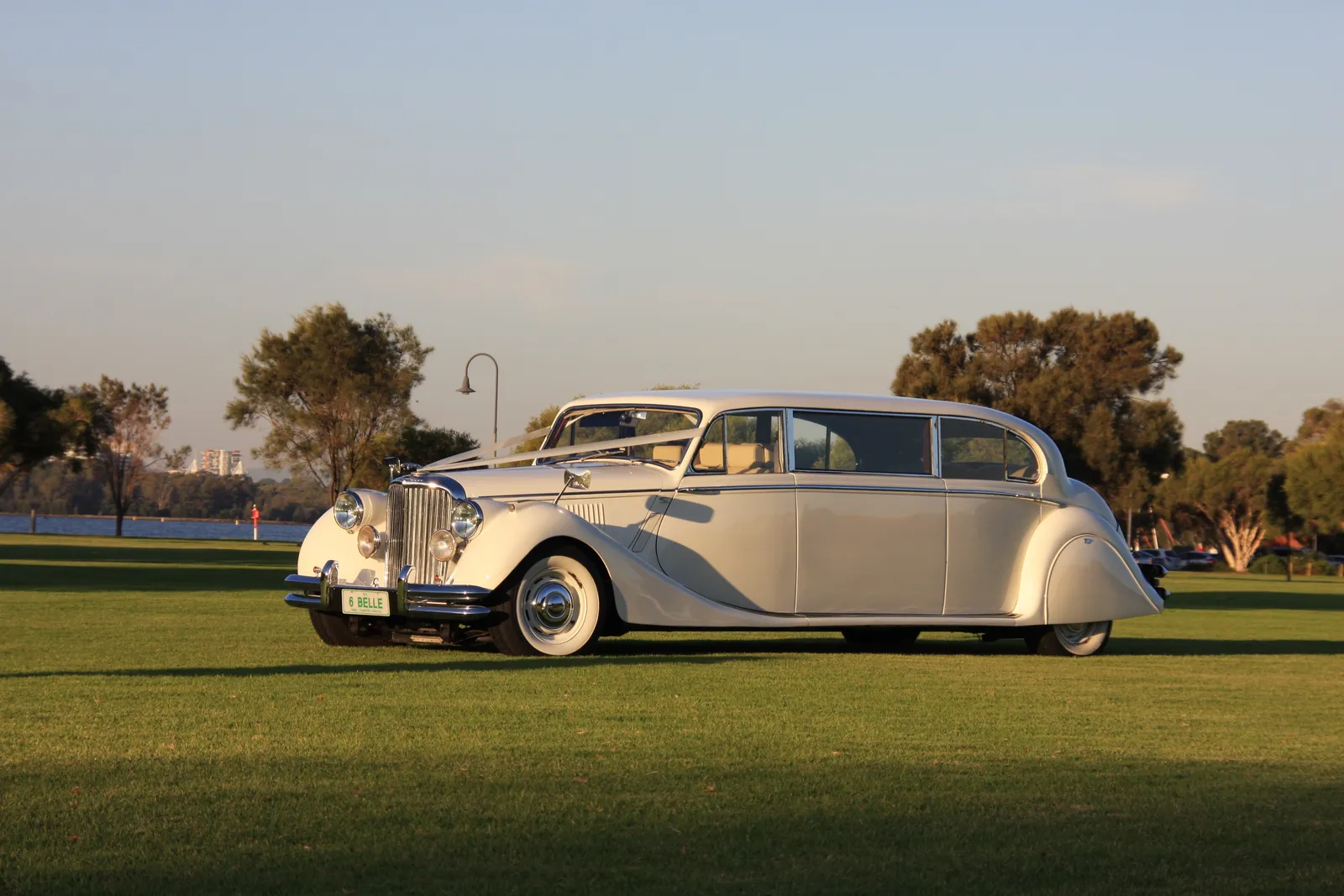 Classic Jaguar sedan wedding car outside a Perth stone church at dusk