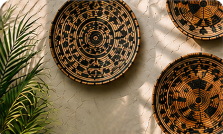 Decorative round woven baskets with intricate patterns on a textured wall next to a green leafy plant.