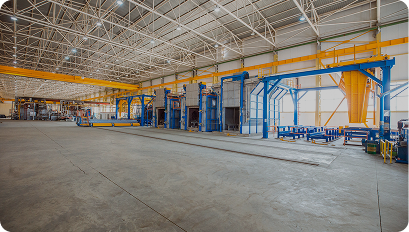 Empty industrial warehouse with large machinery and high metal ceiling structures.