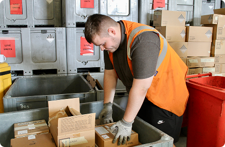Many old electric meters stacked inside cardboard boxes in a storage area.