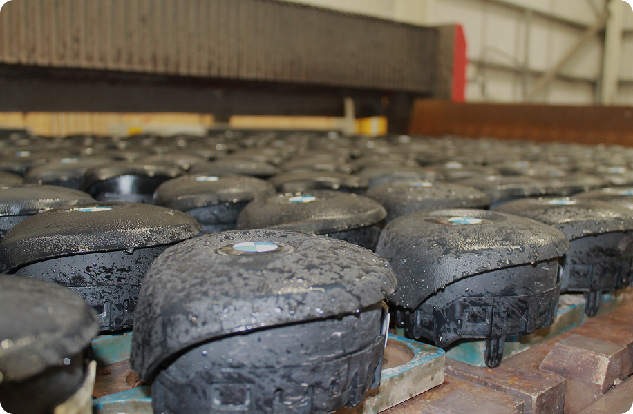 Rows of wet black BMW car airbags lined up on pallets in a manufacturing or storage facility.
