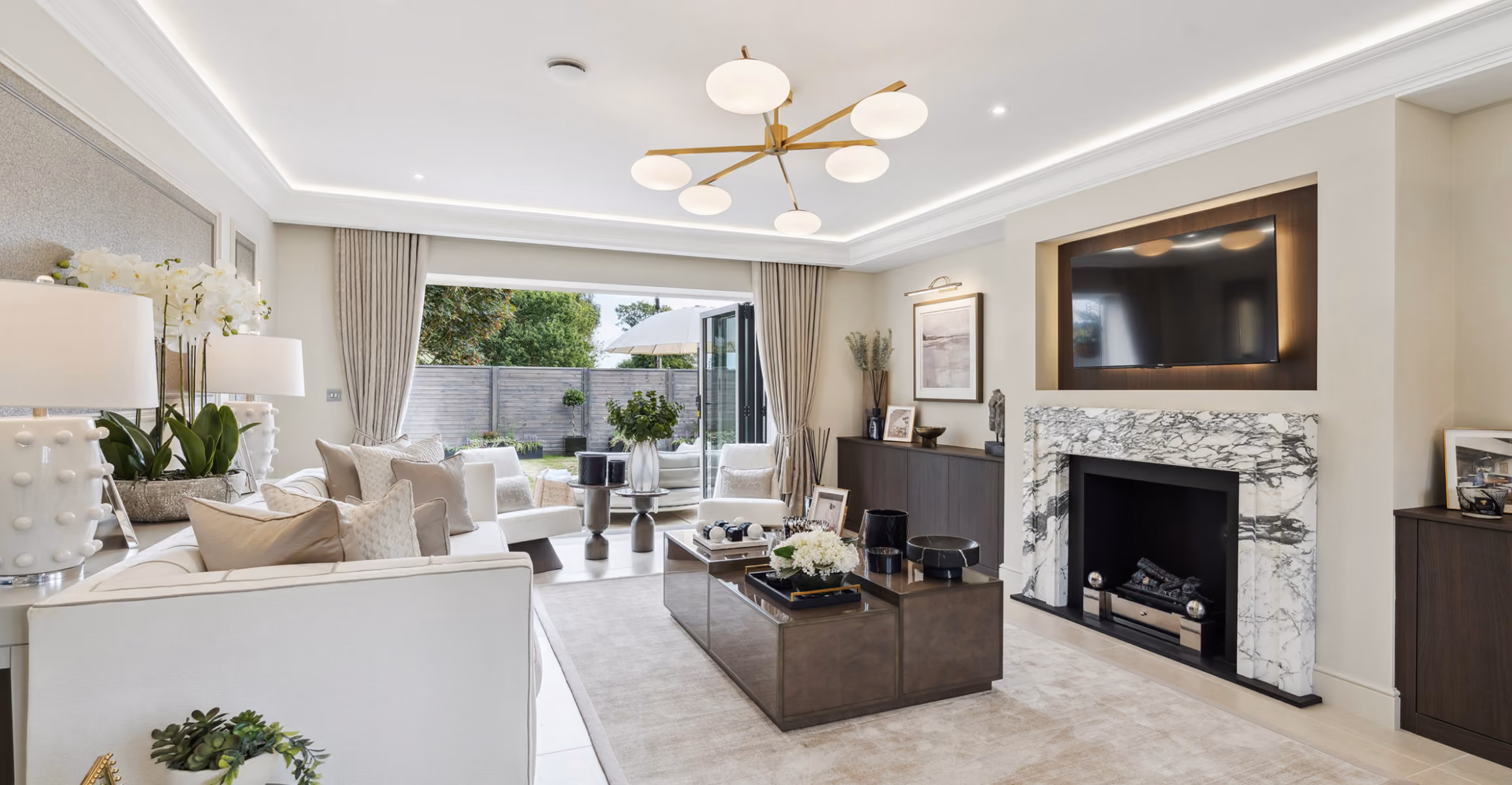Bright modern living room with white furniture, marble fireplace, and open doors to a garden.