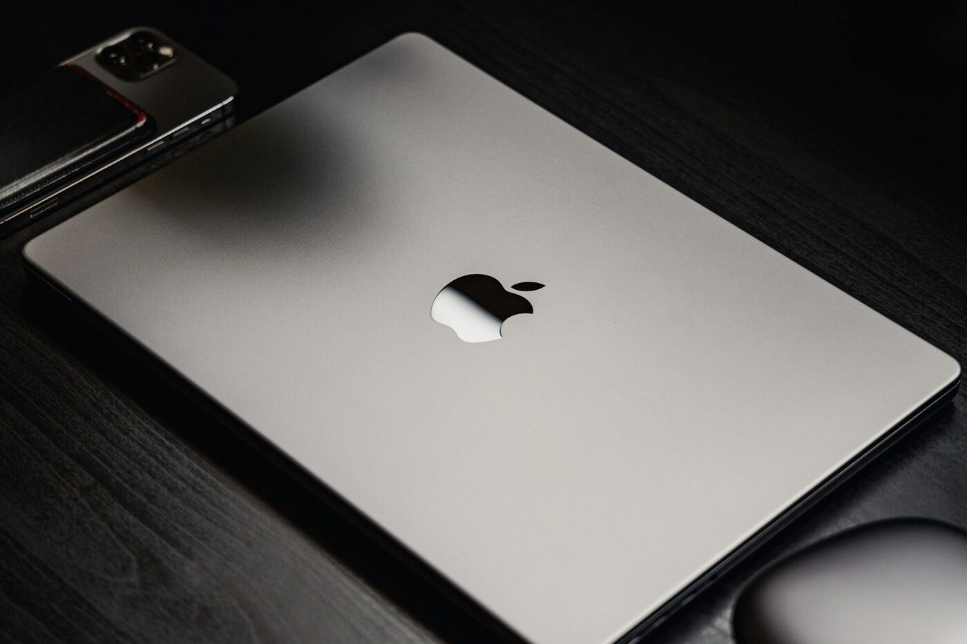 MacBook fermé sur un bureau en bois sombre, réparation Mac et Apple à Argenteuil