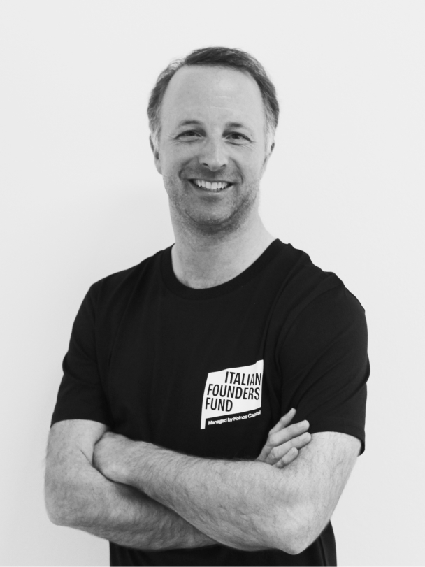 Smiling man with crossed arms wearing a black Italian Founders Fund t-shirt.