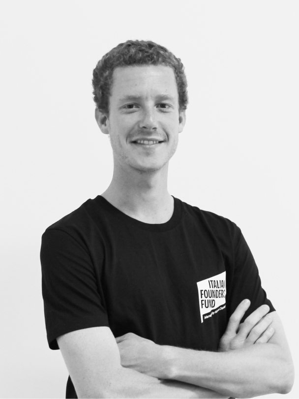 Man with curly hair smiling and crossing arms wearing a black T-shirt with an Italian Founders Fund logo.