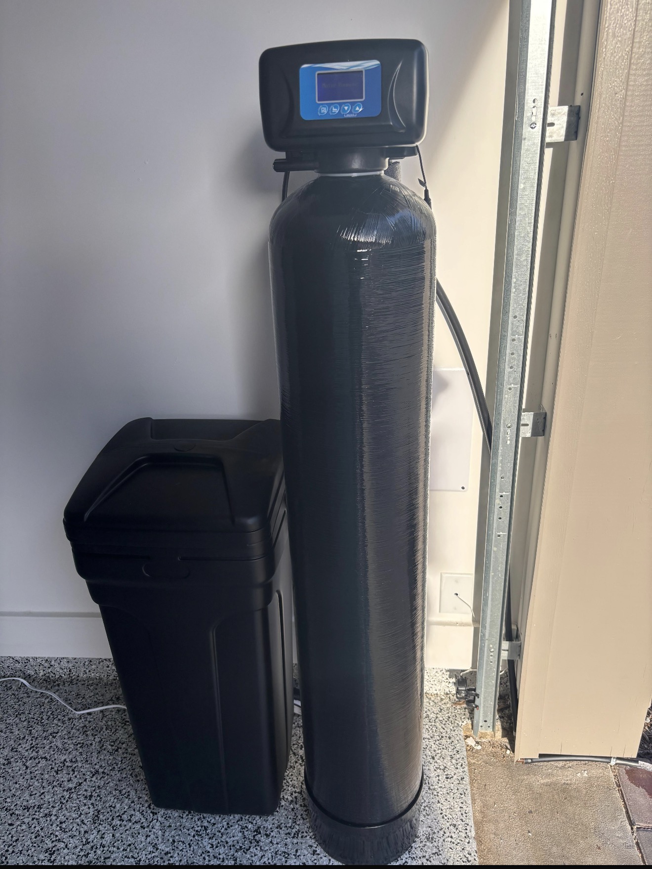 Whole-home water softener installed in a garage