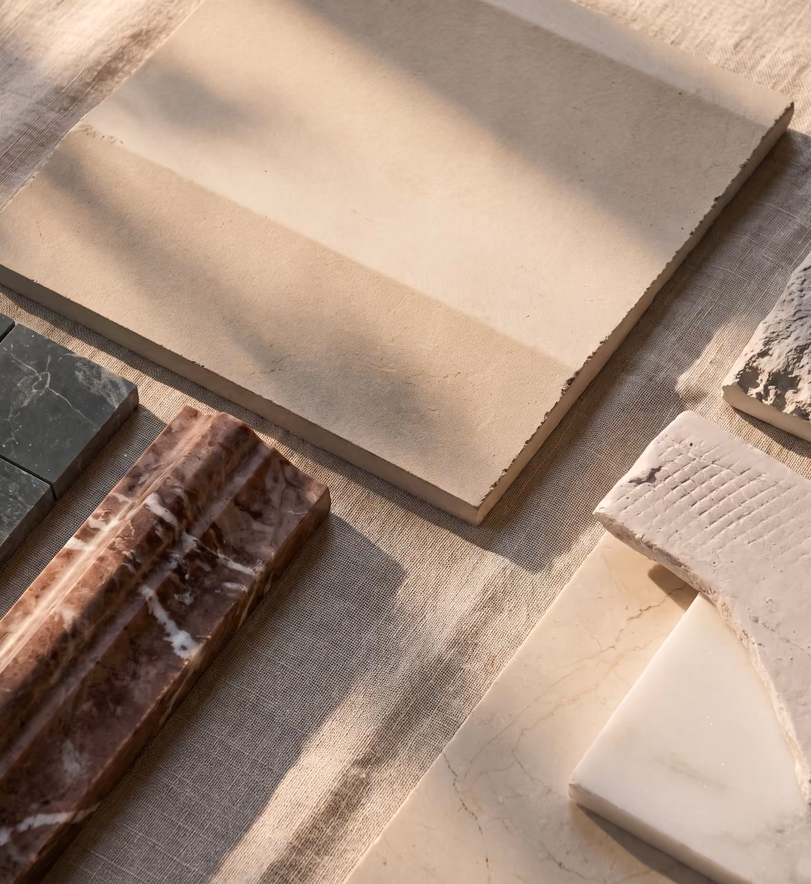 Tile samples of various ceramic and stone types laid out on a linen sheet