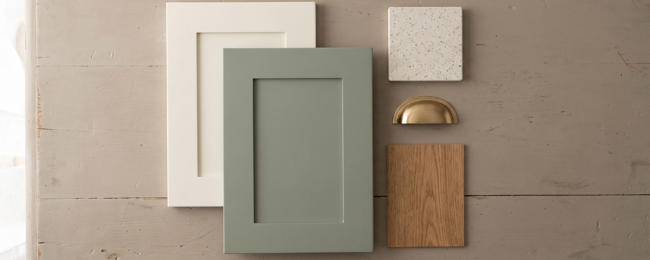Flat lay of two paired cabinet door samples, a quartz chip, and hardware for a two-tone kitchen.