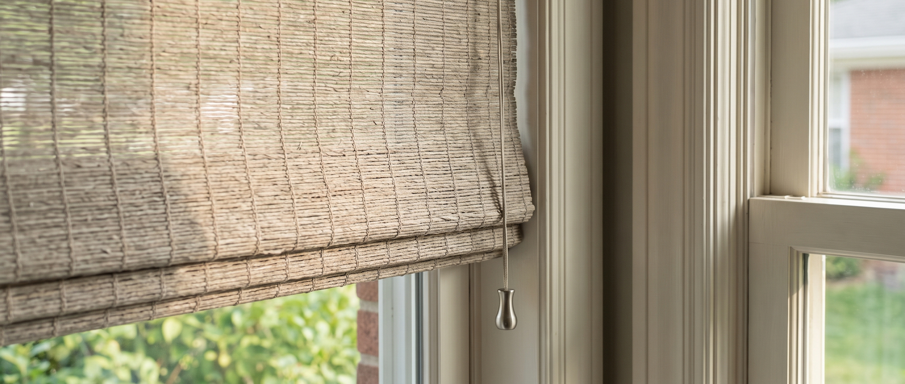 Close-up of a woven shade texture at a sunlit window.