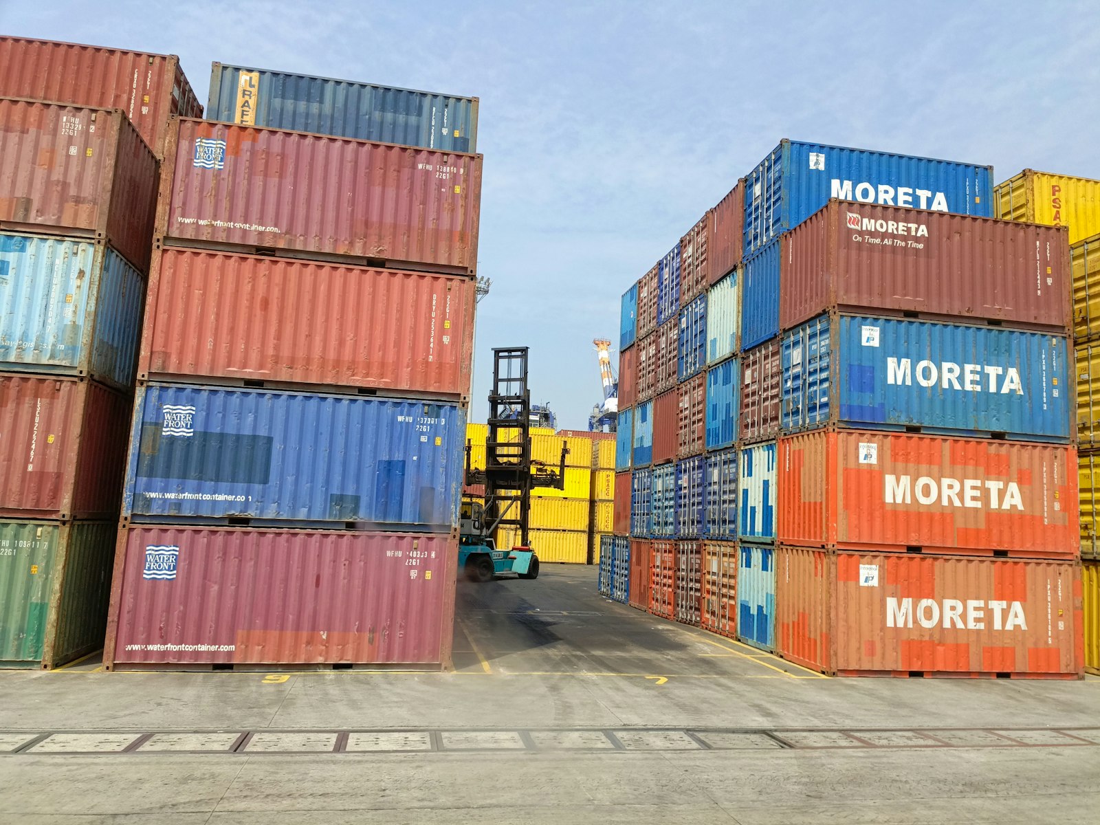 Forklift loading stacked shipping containers at a port