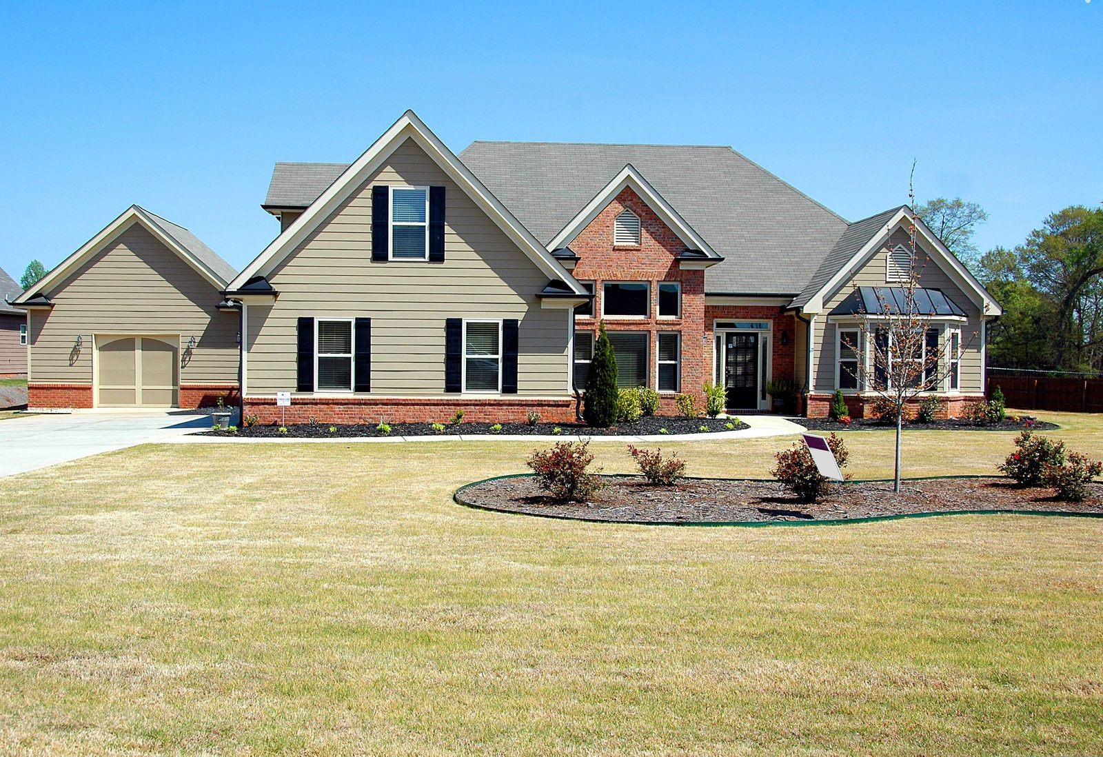 Front exterior of a suburban single-family home with an attached two-car garage, brick and siding facade, and a landscaped front lawn.