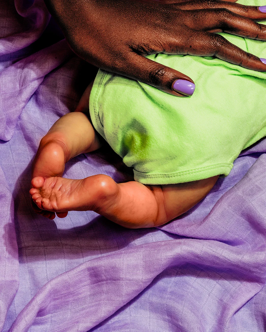 Gentle close-up of a mother's hand holding tiny newborn baby feet