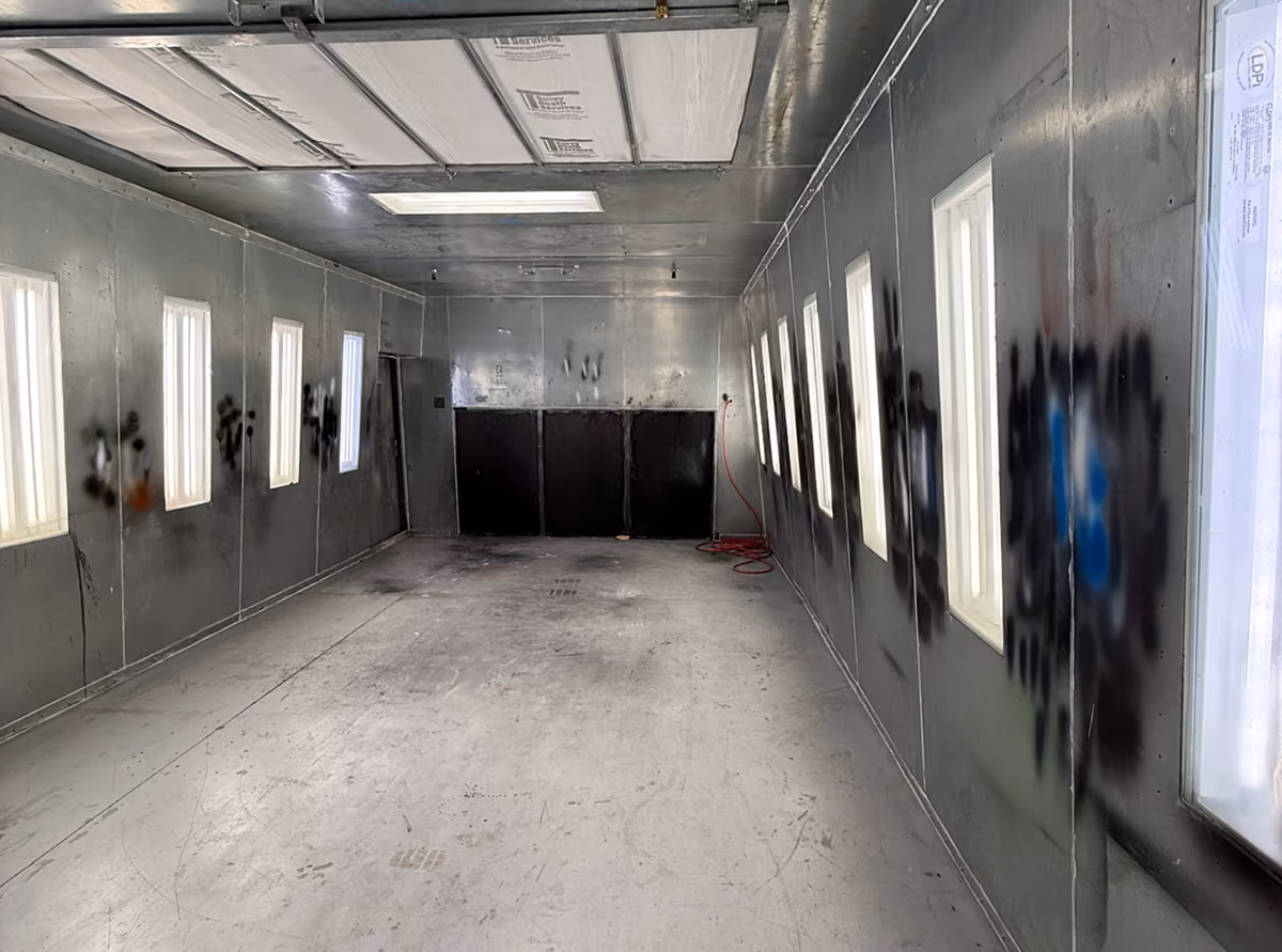 Long empty metal room with windows on both sides and a ceiling panel.