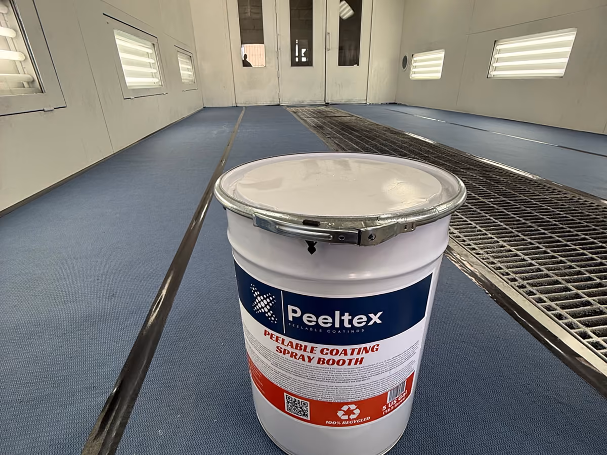 A container of Peeltex peelable coating spray booth inside a clean industrial spray booth.