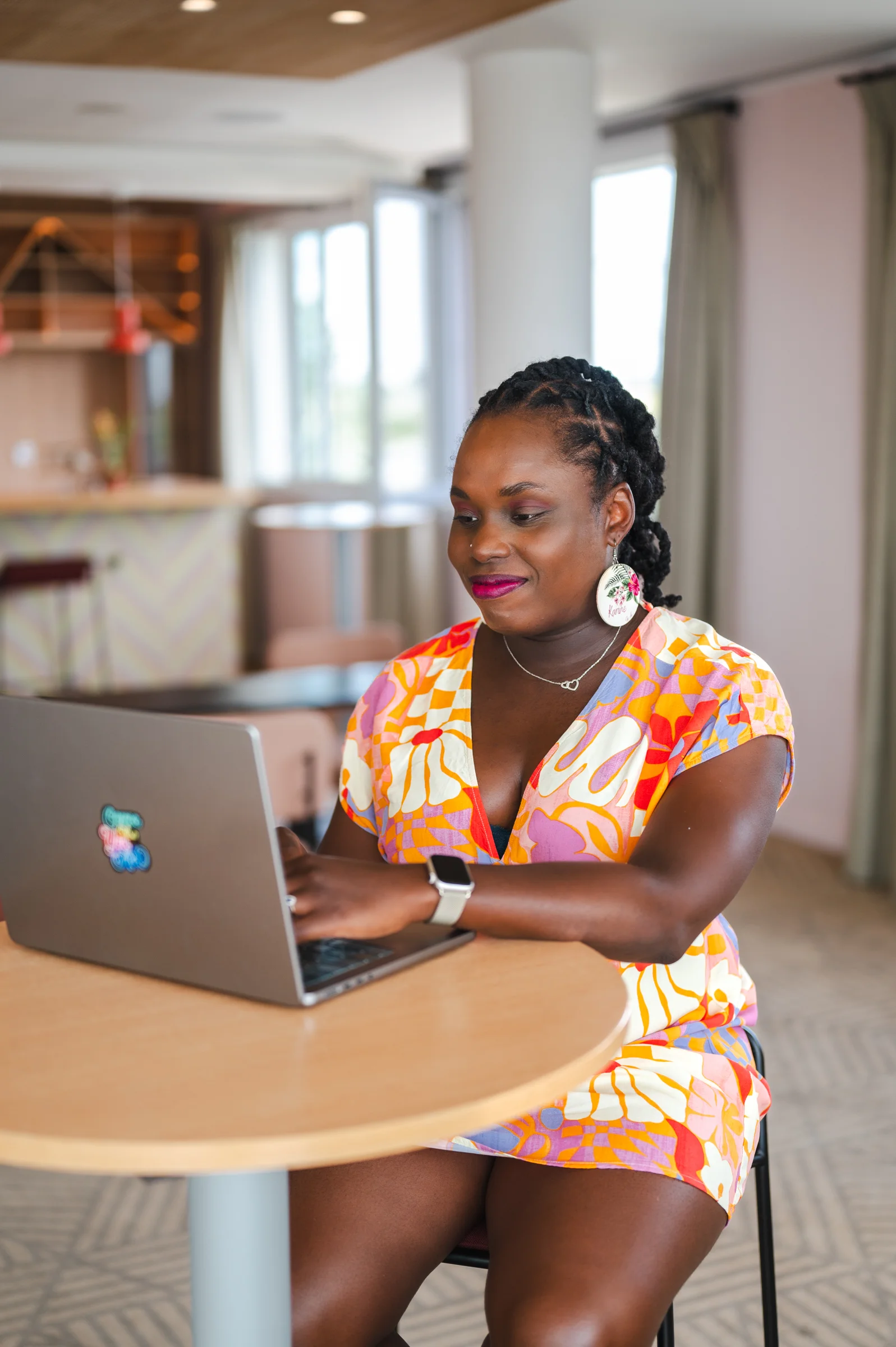 Portrait de Karine, webdesigner freelance, souriante en train de travailler sur son ordinateur portable.