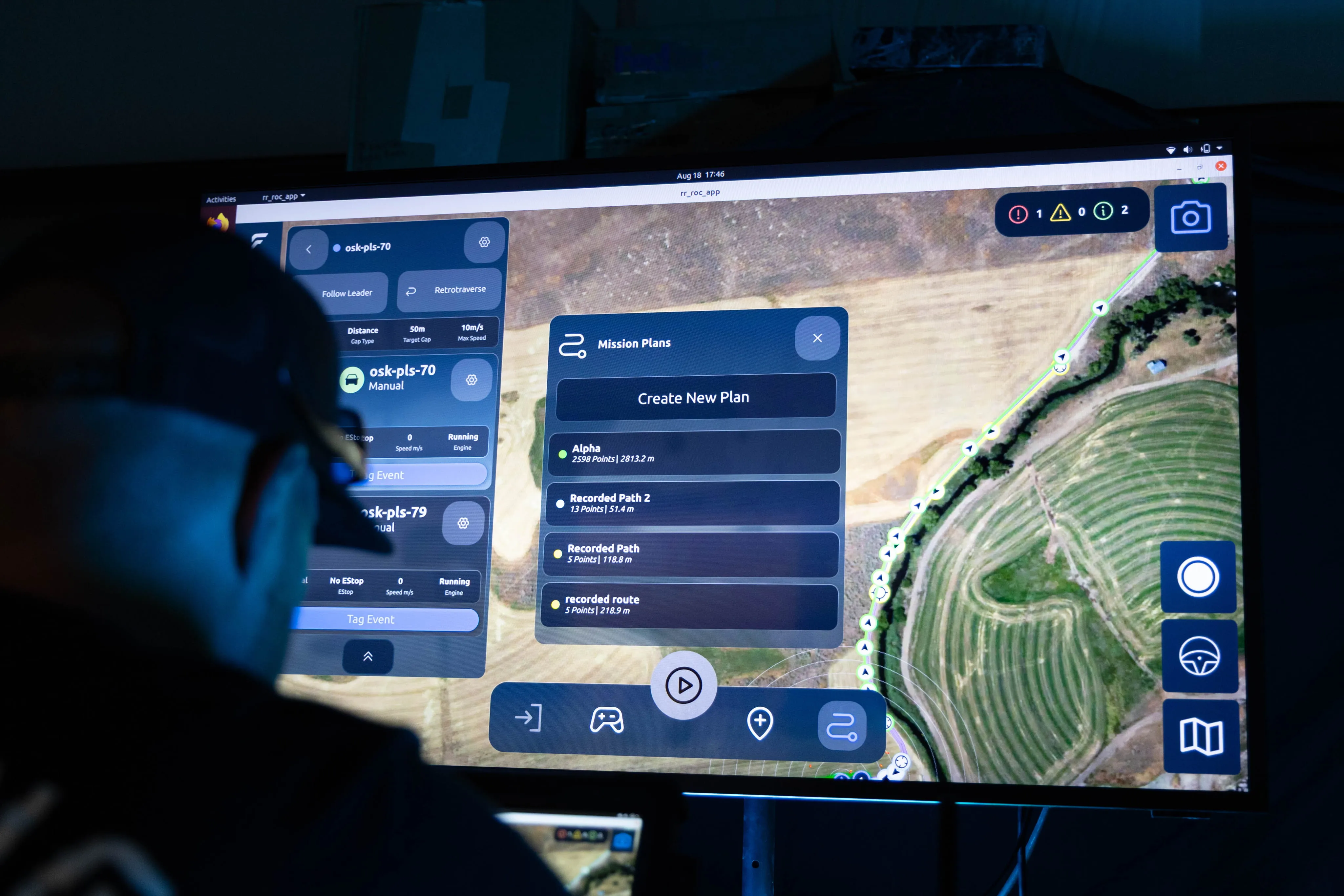 Person wearing headset viewing a map-based mission planning interface on a large screen.