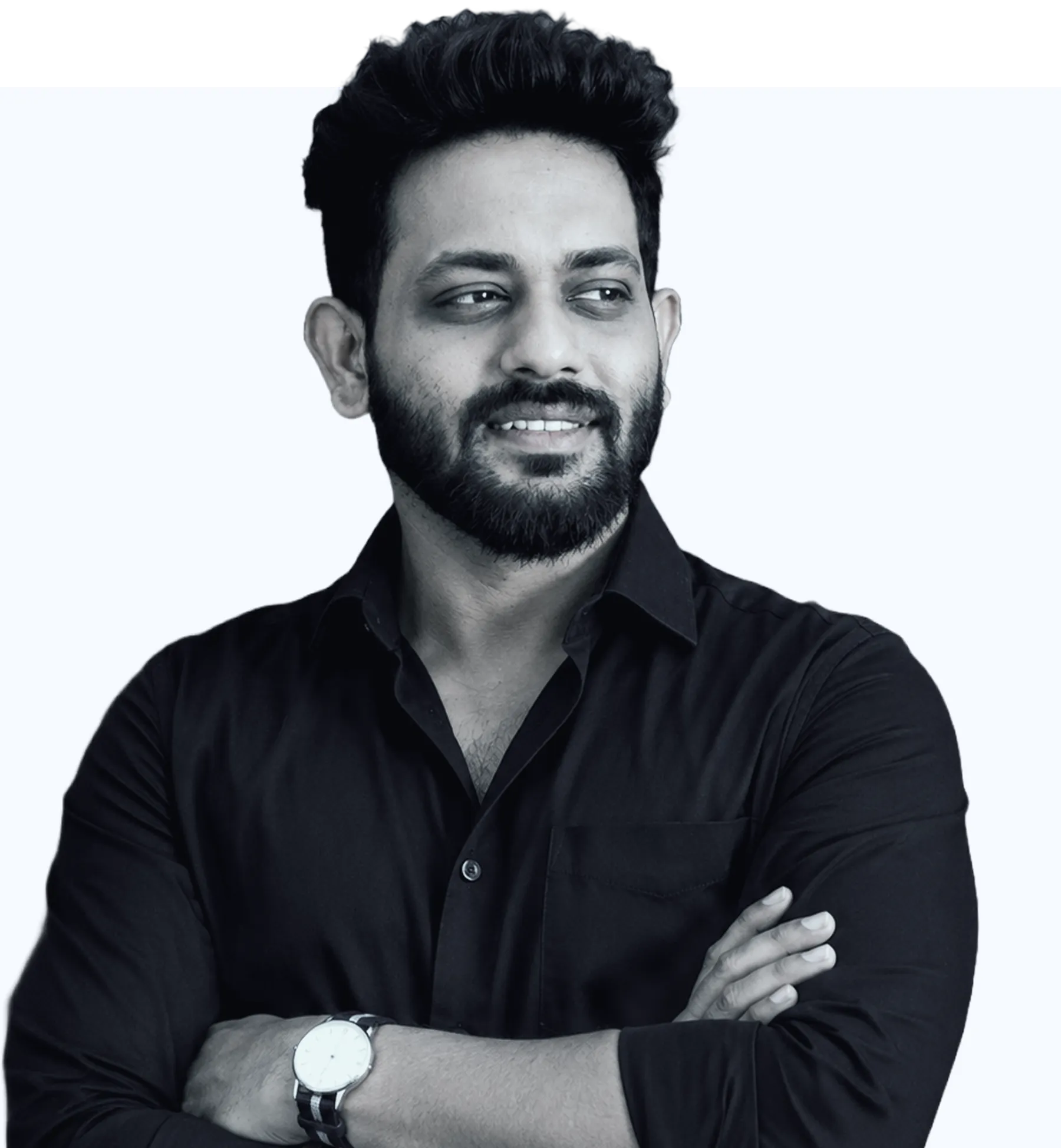 Smiling man with beard wearing a black suit looking to his left on a light background.