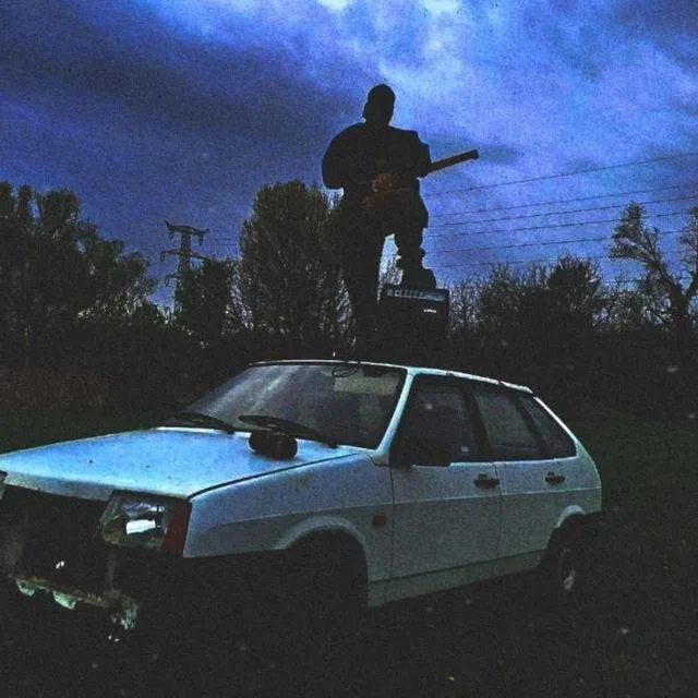 anatu, music producer, silhouetted on a car at dusk