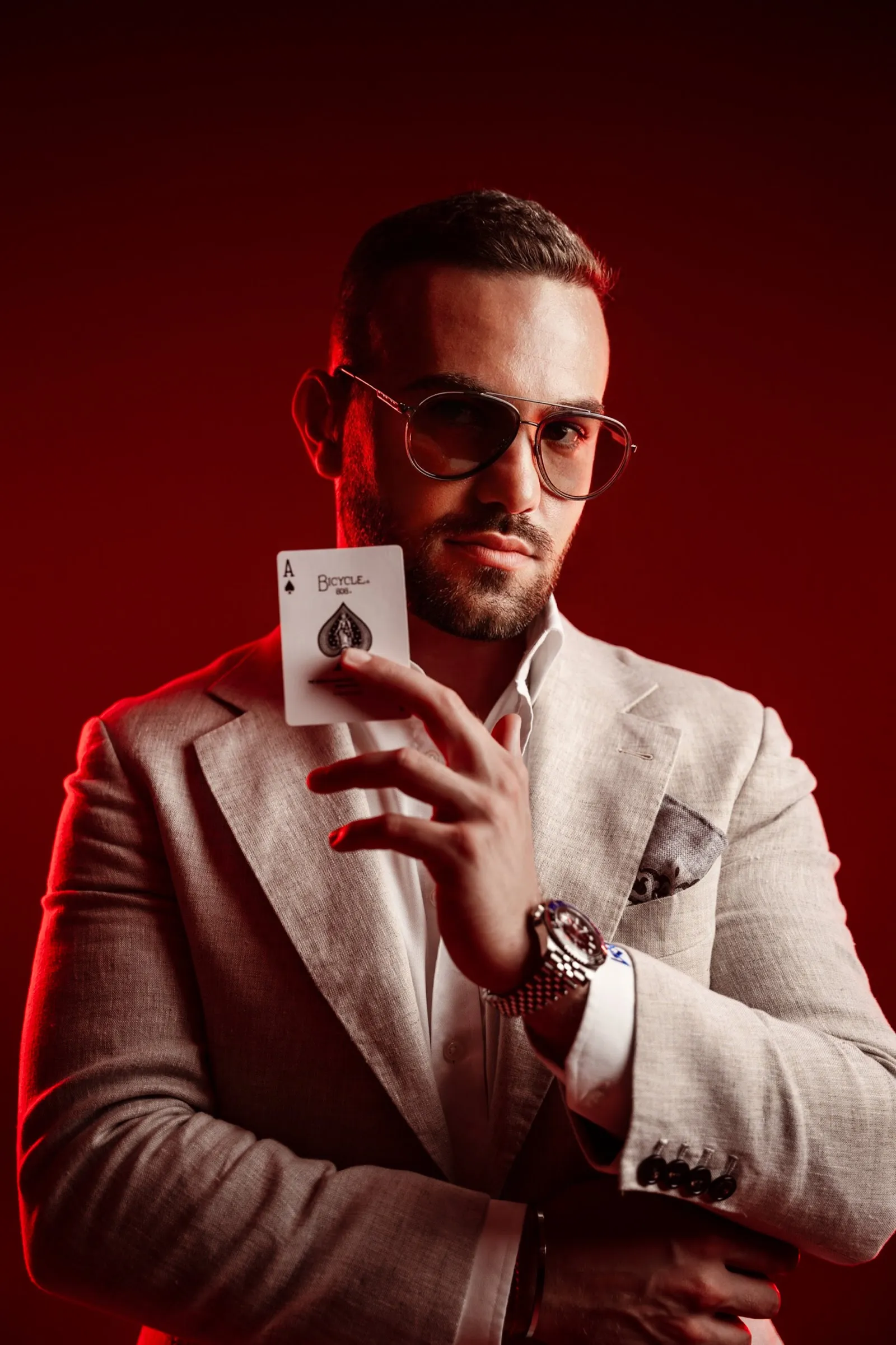 Magician Matteo Cammisa holding an ace of spades against a red backdrop