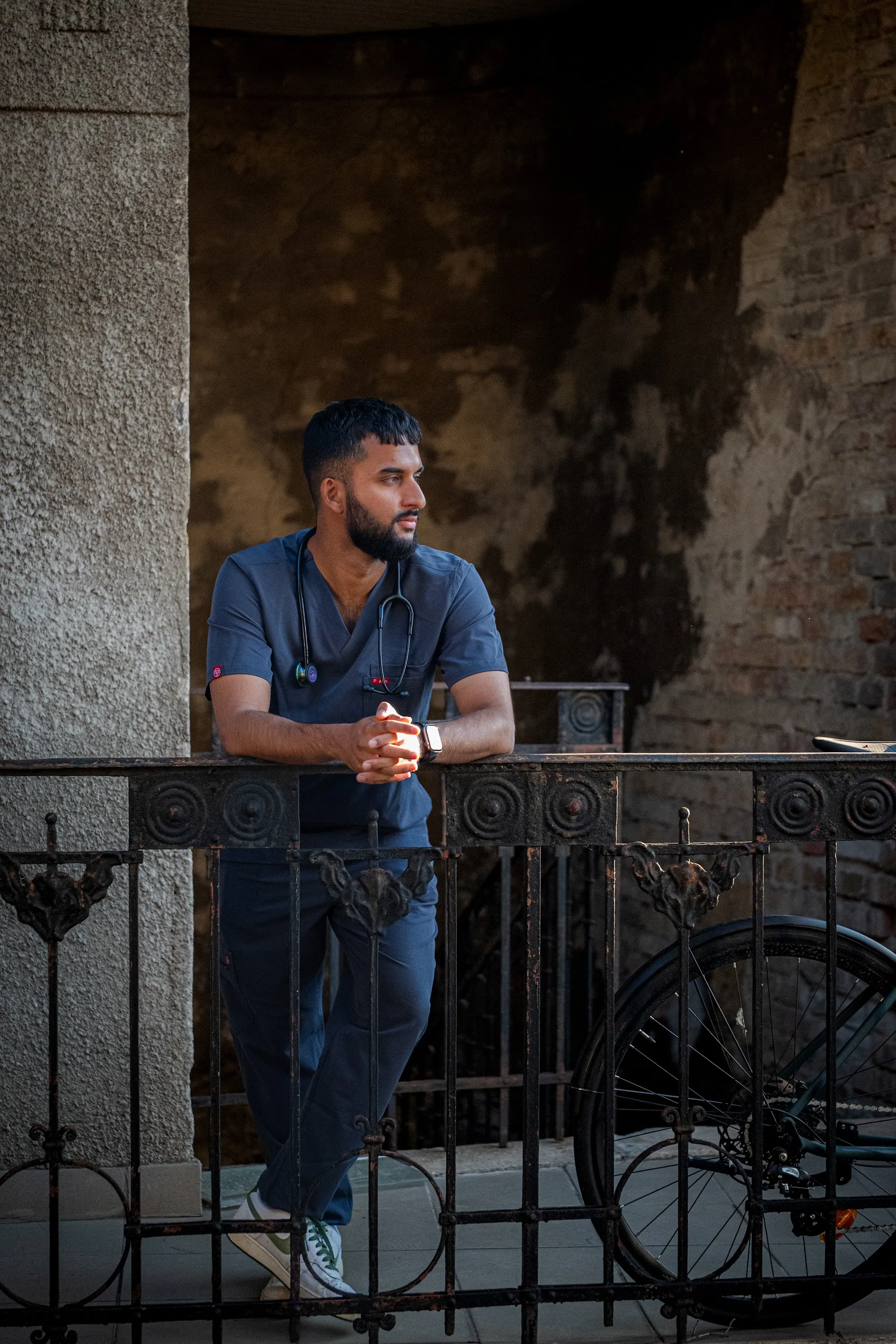 Model Zoubi standing at a wrought-iron railing in a stone courtyard, portrait by GROOVE Media