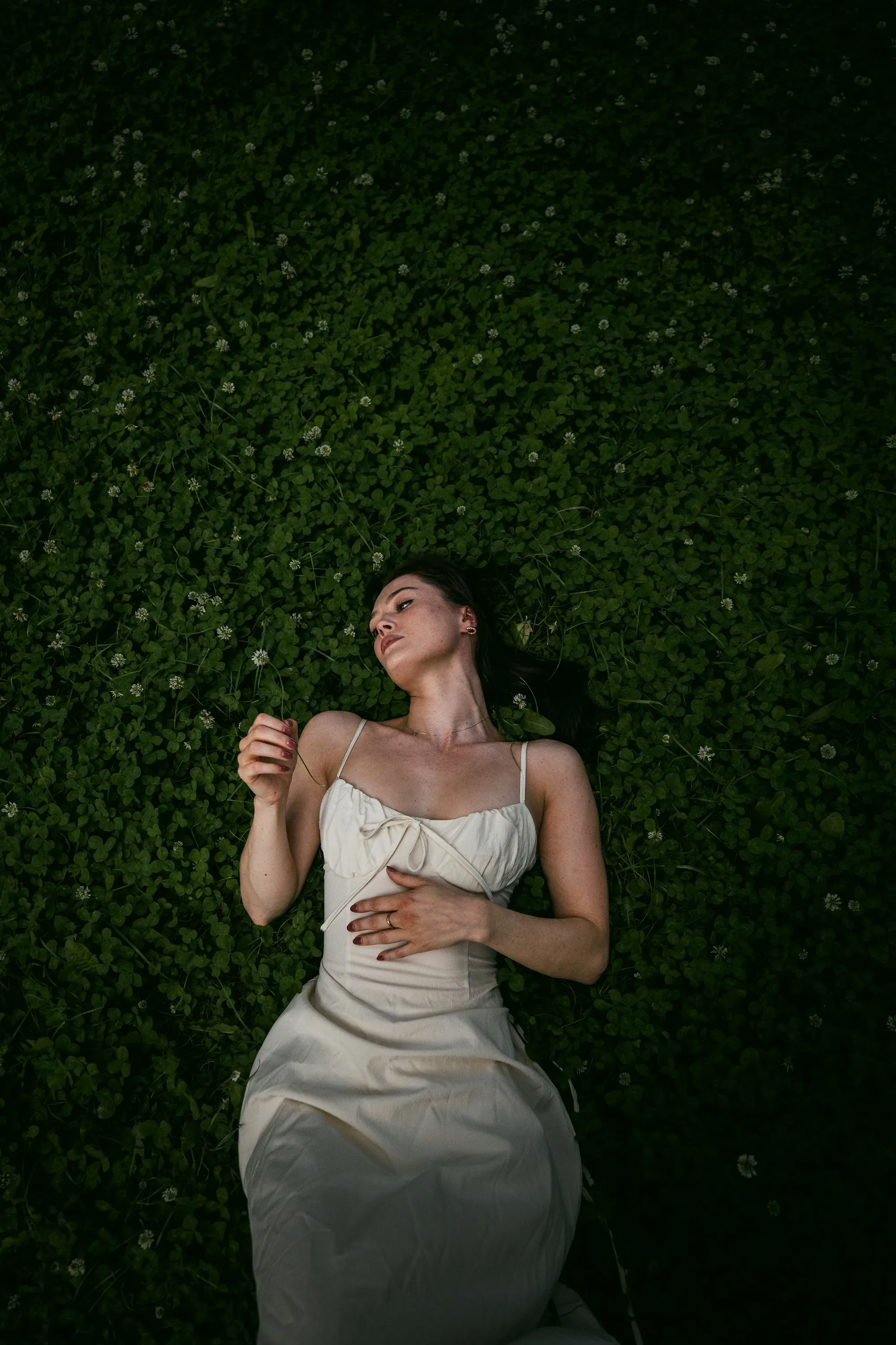 Model Julia lying in a bed of clover, In White editorial by GROOVE Media