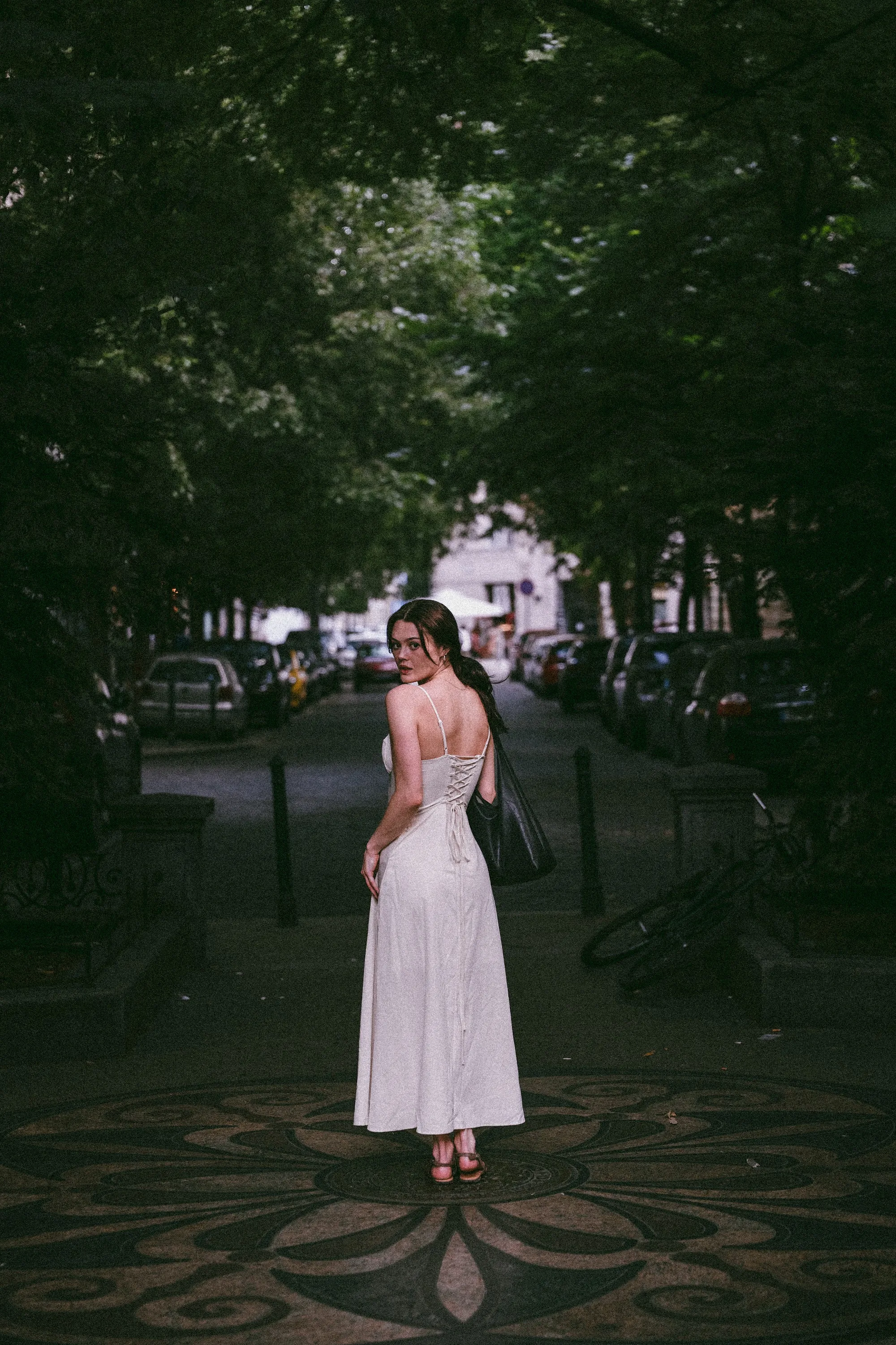 Model Julia in a white dress on a mosaic plaza at dusk, In White editorial by GROOVE Media