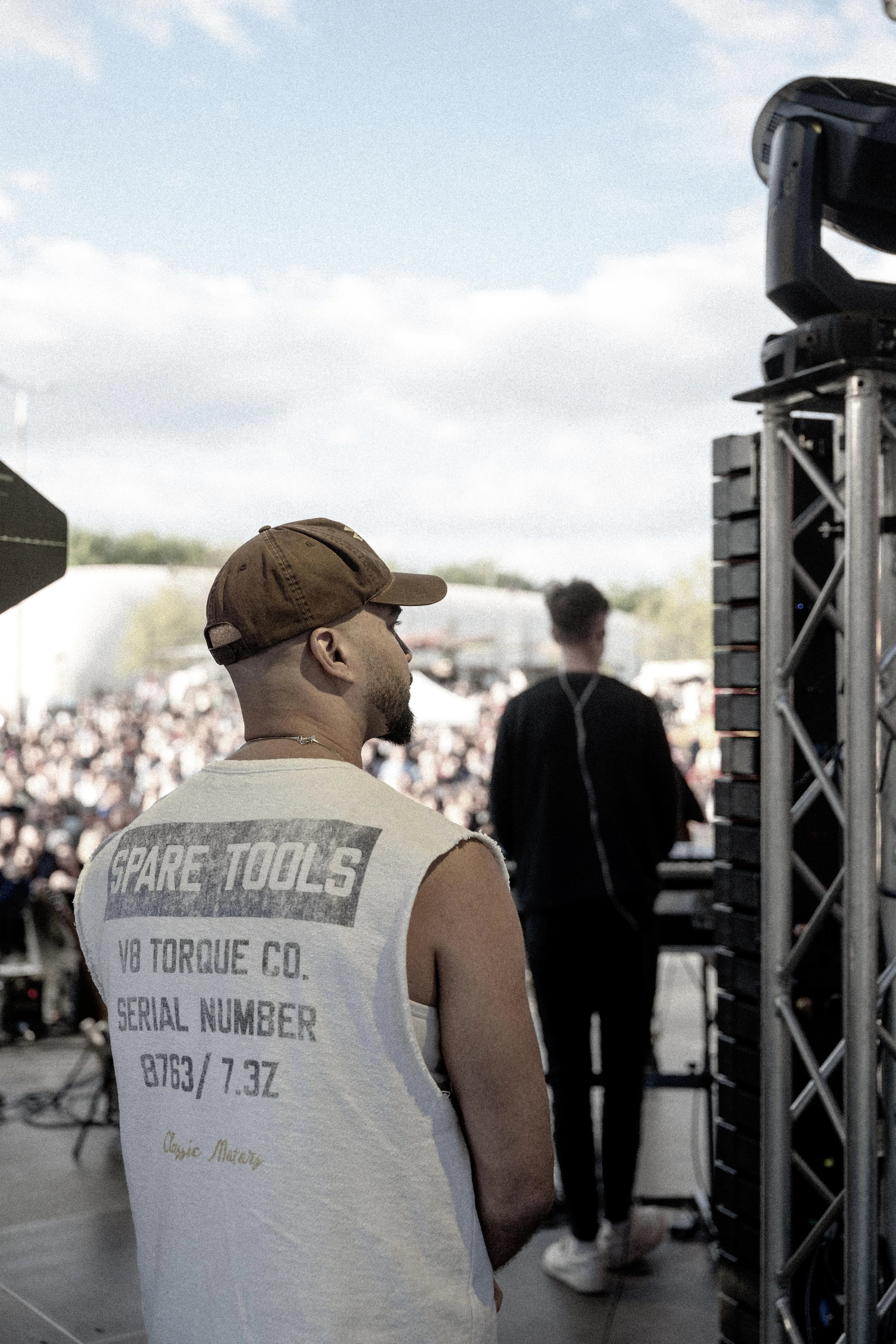 View from the side of the stage past the artist toward a festival crowd, concert photography by GROOVE Media