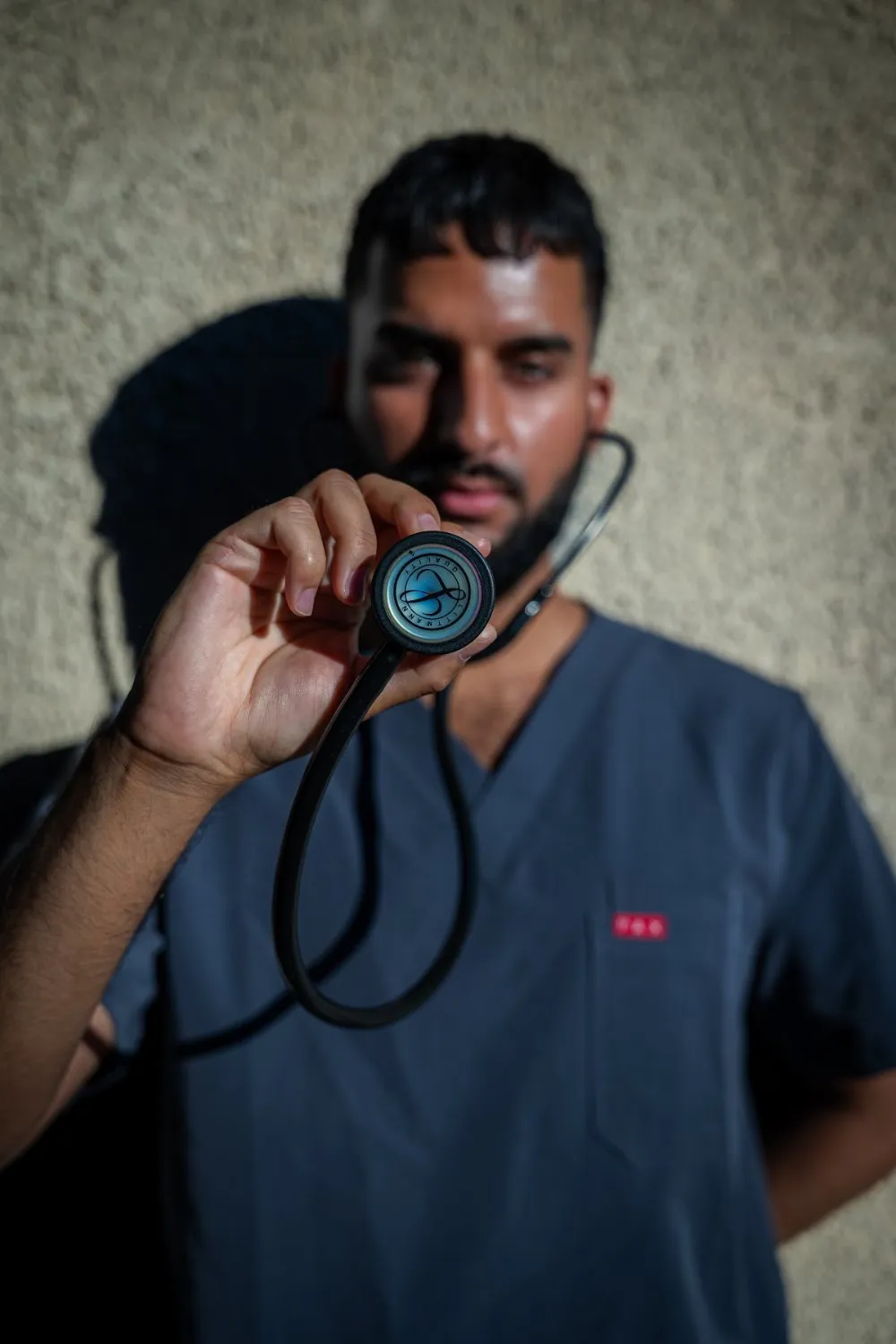Zoubi holding a stethoscope toward the camera in PAX Scrubs, campaign photography by GROOVE Media