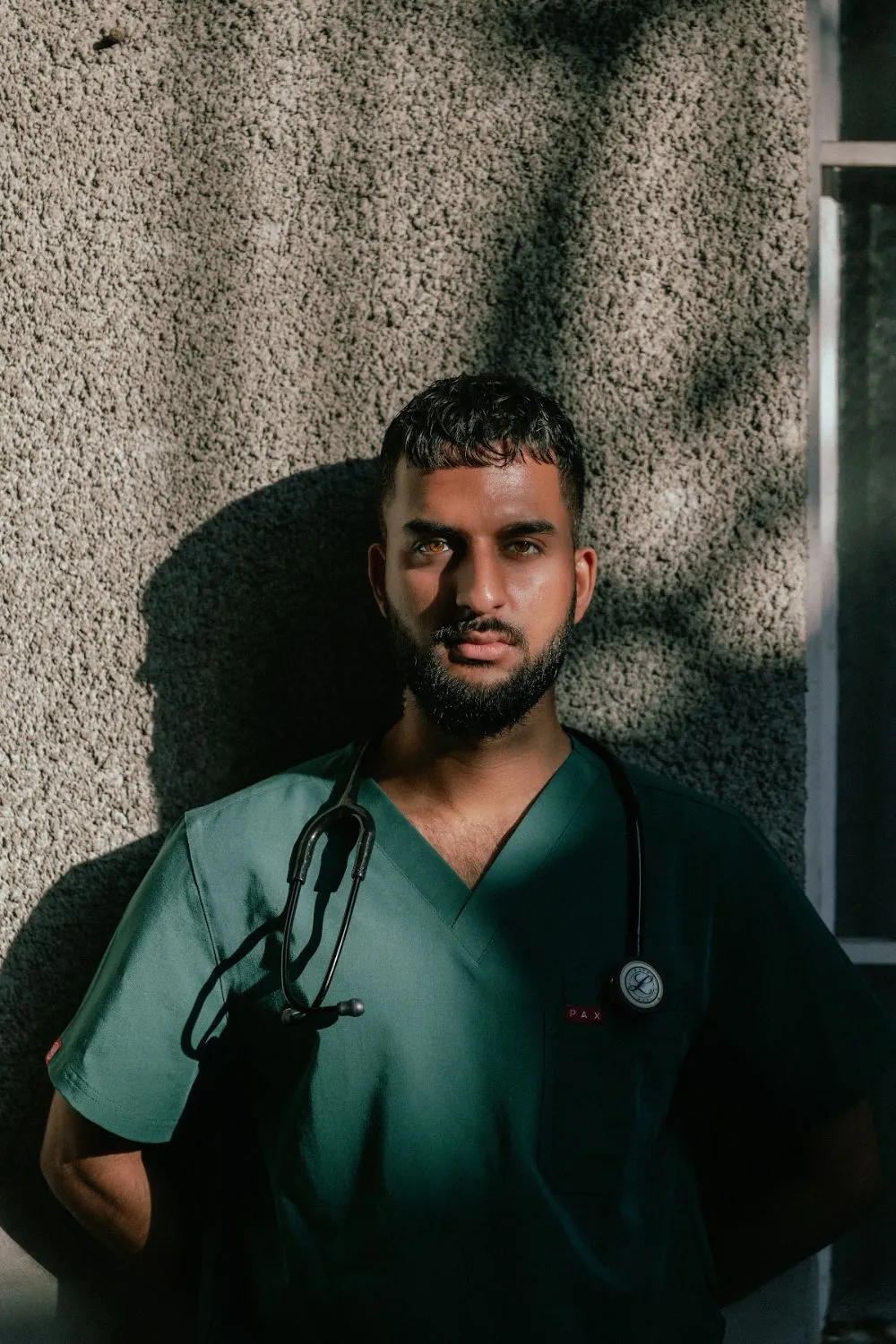 Zoubi in teal PAX Scrubs with a stethoscope in dappled shadow, PAX Scrubs campaign