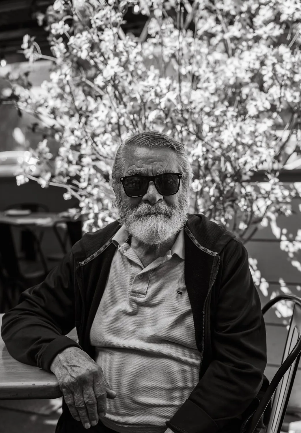 Behrouz Vossoughi in sunglasses under spring blossoms, black-and-white portrait by GROOVE Media
