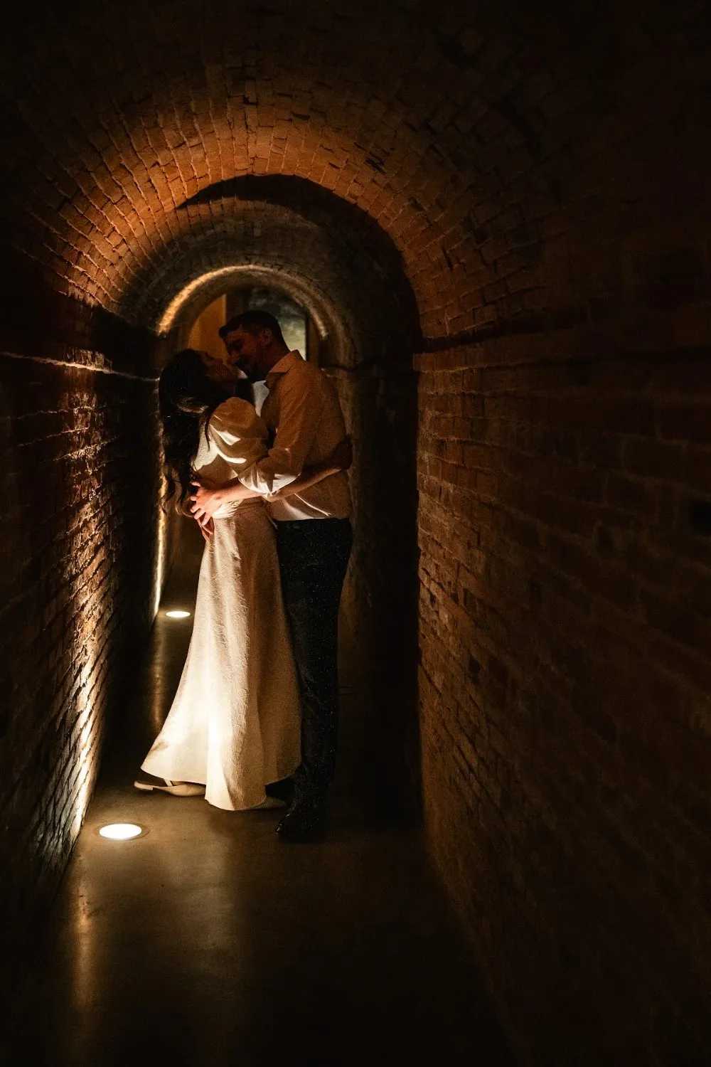 Couple embracing in a candlelit brick tunnel, wedding photography by GROOVE Media