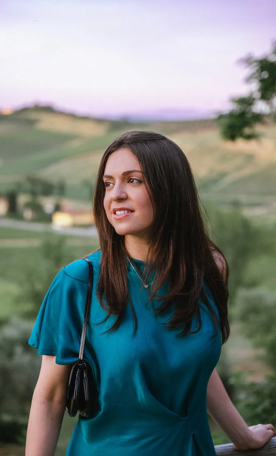 Wedding guest in a teal dress against the vineyard hills at golden hour, by GROOVE Media