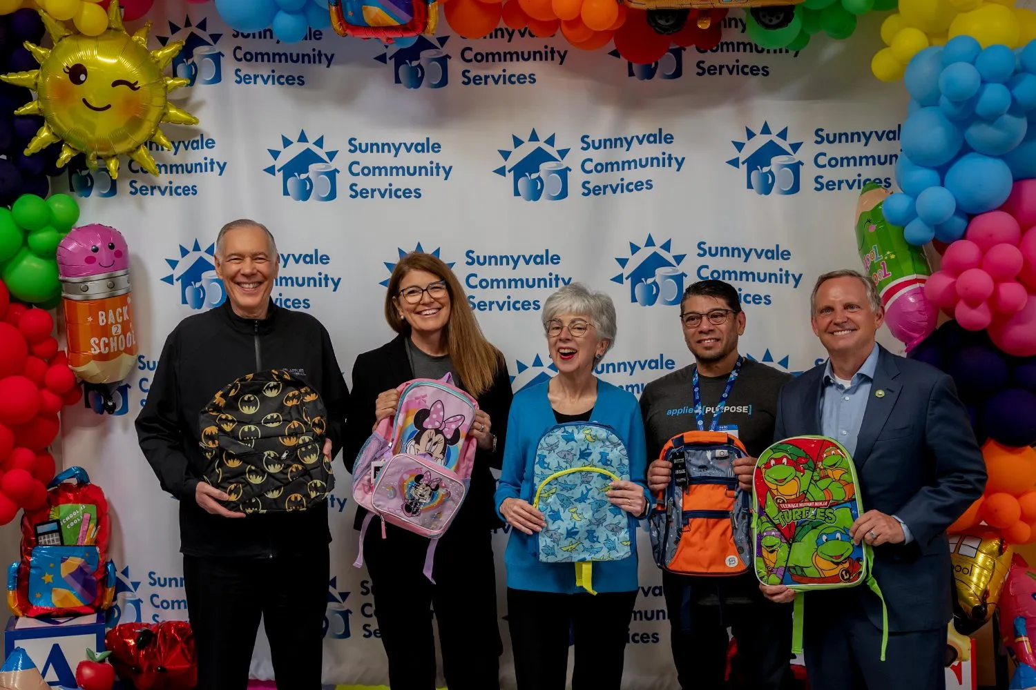Organizers holding donated backpacks in front of the Sunnyvale Community Services building
