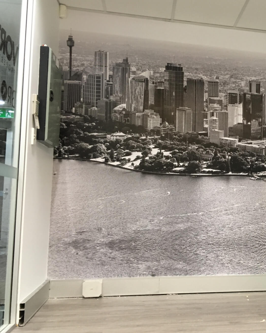 Black and white wall mural of a city skyline with tall buildings and waterfront in an indoor office.