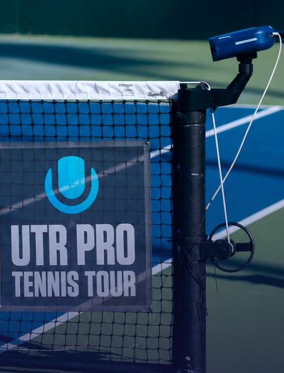Close-up of tennis net post with UTR Pro Tennis Tour banner and blue tennis court background.