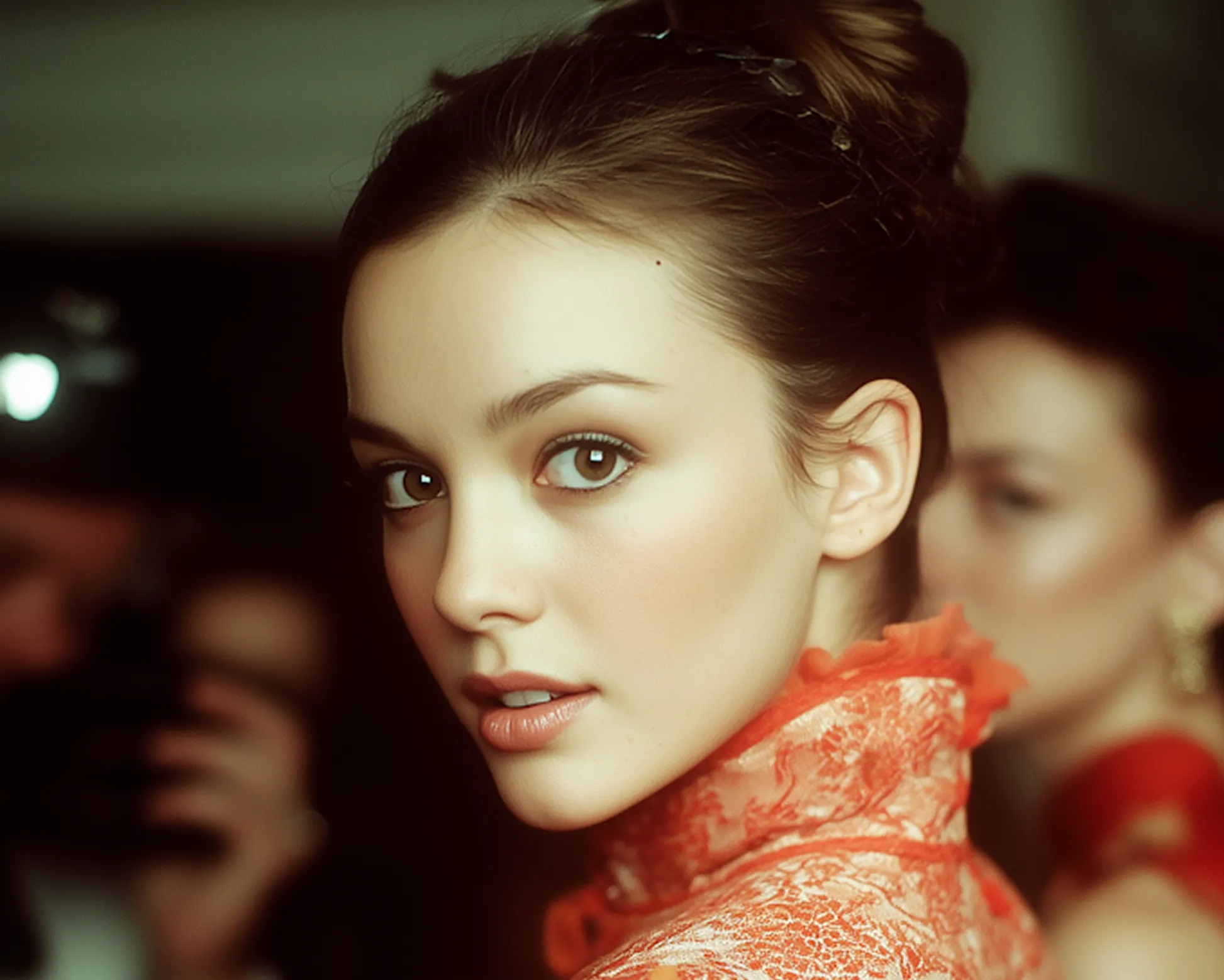Young woman with brown eyes and hair in an updo wearing an orange lace high-collared dress.