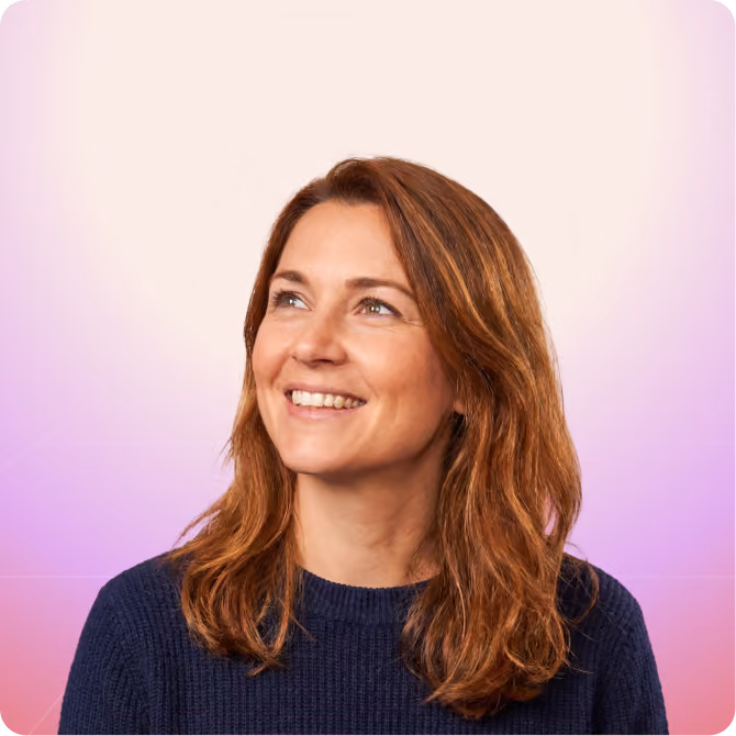 Smiling RevOps partner with shoulder-length auburn hair wearing a navy blue sweater, looking upwards.