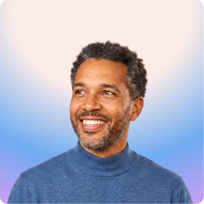 Smiling channel partner manager with curly salt-and-pepper hair and beard wearing a blue turtleneck sweater looking to the side.