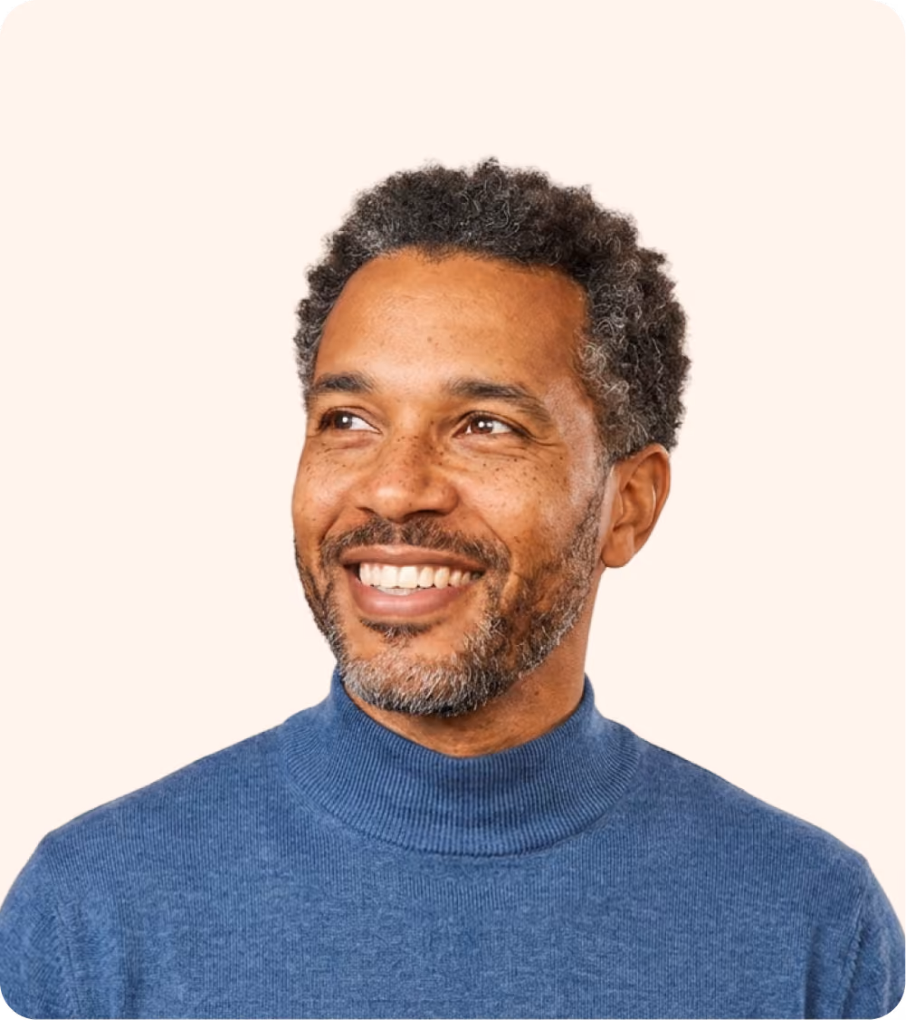 Smiling channel partner manager with curly salt-and-pepper hair and beard wearing a blue turtleneck sweater looking to the side.