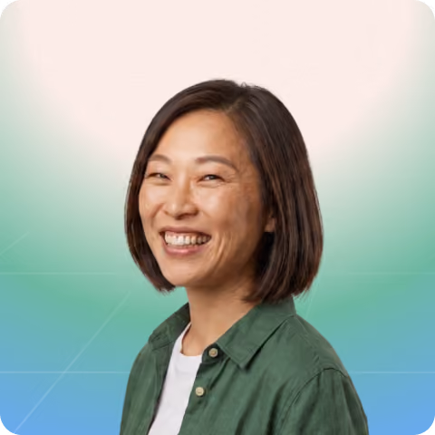 Smiling CRO partner with short black hair wearing a green shirt over a white top on a gradient background.