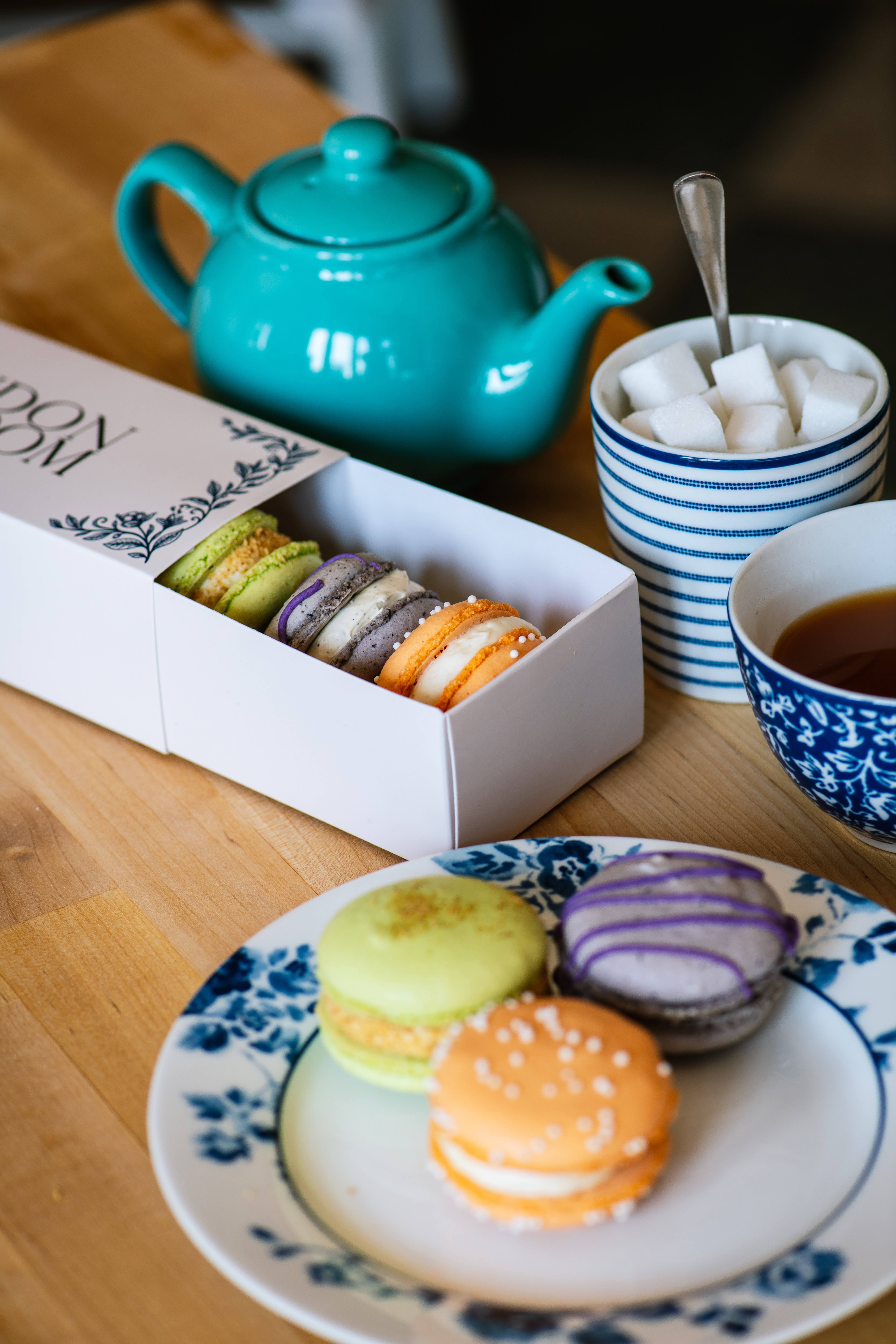 A box of French macarons with blue-and-white china and tea