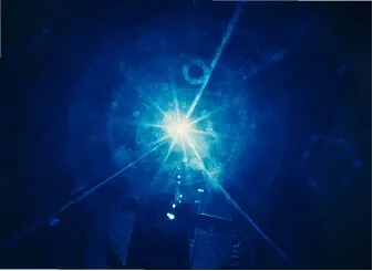 Bright blue light flare with lens reflections against a dark background.