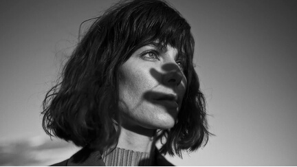 Black and white portrait of a woman with short hair looking to the right with shadow on her face.
