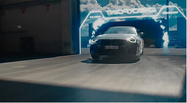 Black sports car driving through a tunnel with illuminated futuristic blue light patterns.
