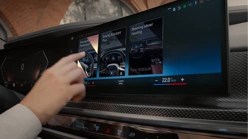 Hand interacting with a car touchscreen menu showing options for steering wheel heating and related features.