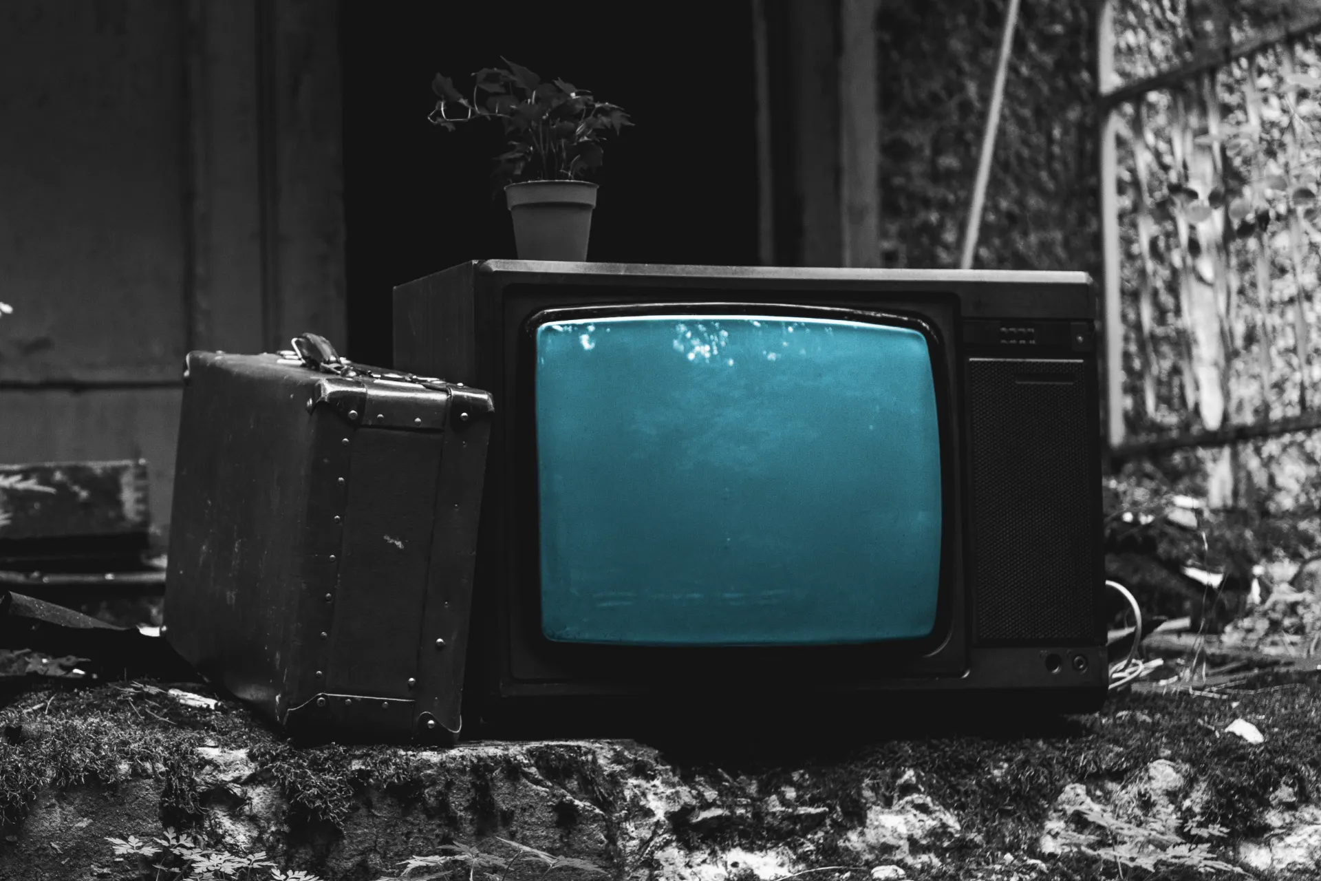 Retro TV with a blue screen in a messy ran down yard